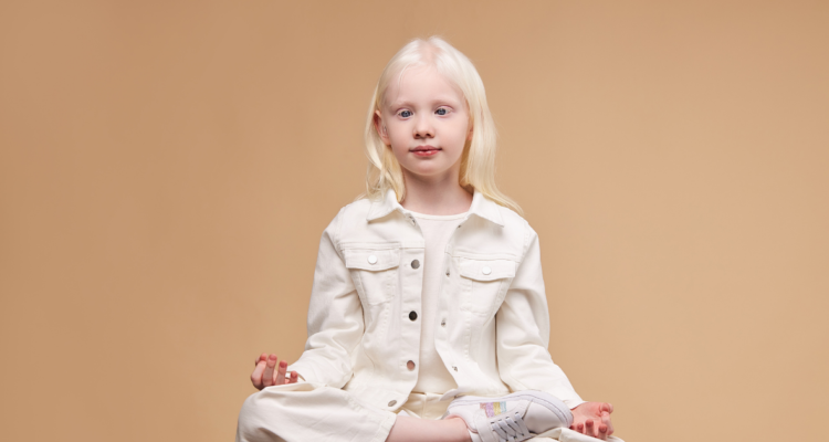 bambina albina seduta con posa zen