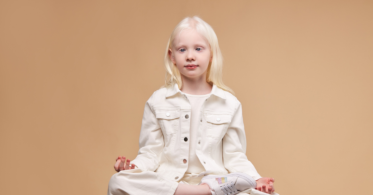 bambina albina seduta con posa zen
